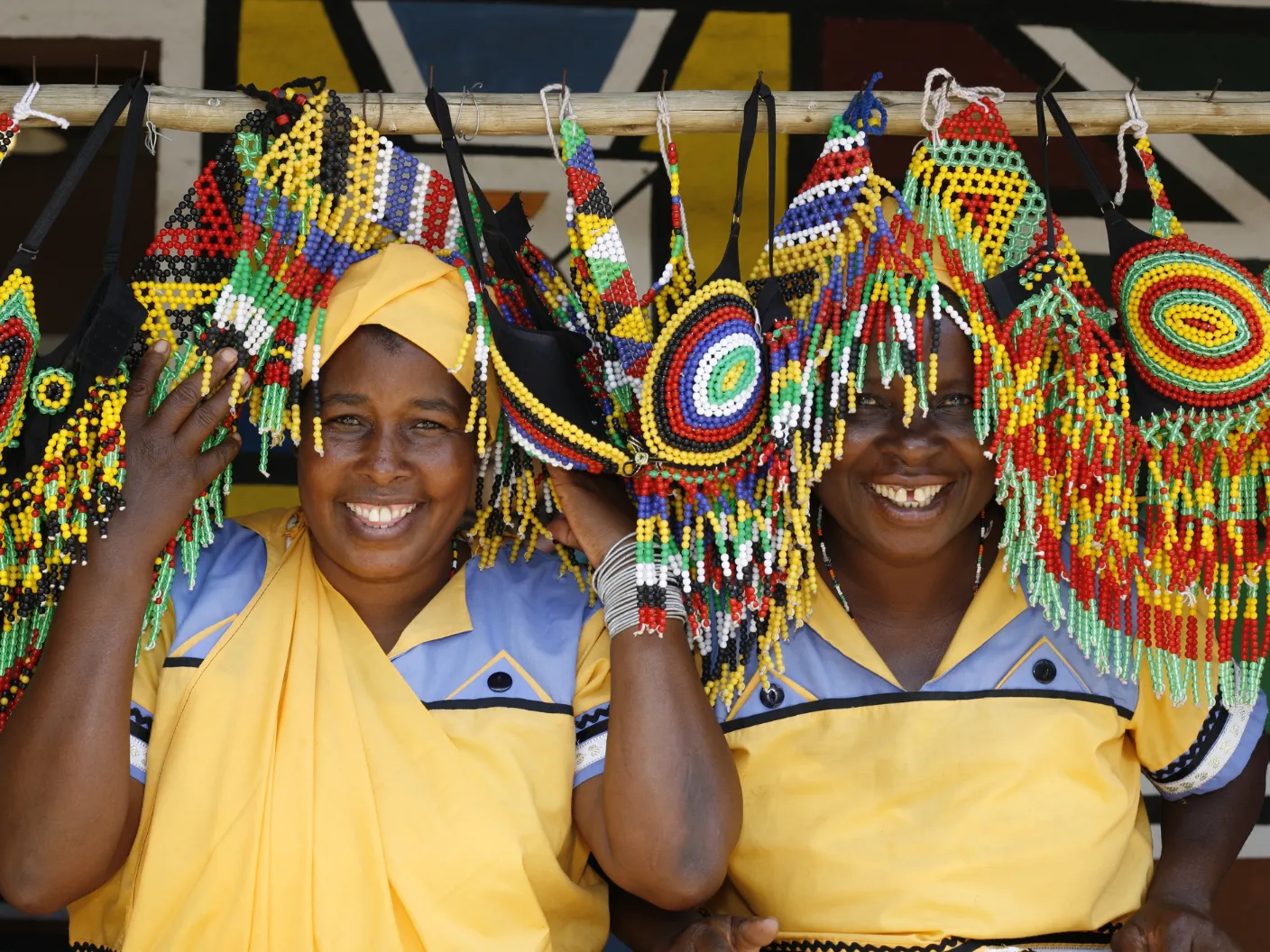 Two traders holding up beadwork at a market stall